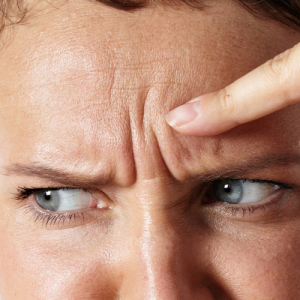 Woman touching her wrinkles on a forehead with disappointed face