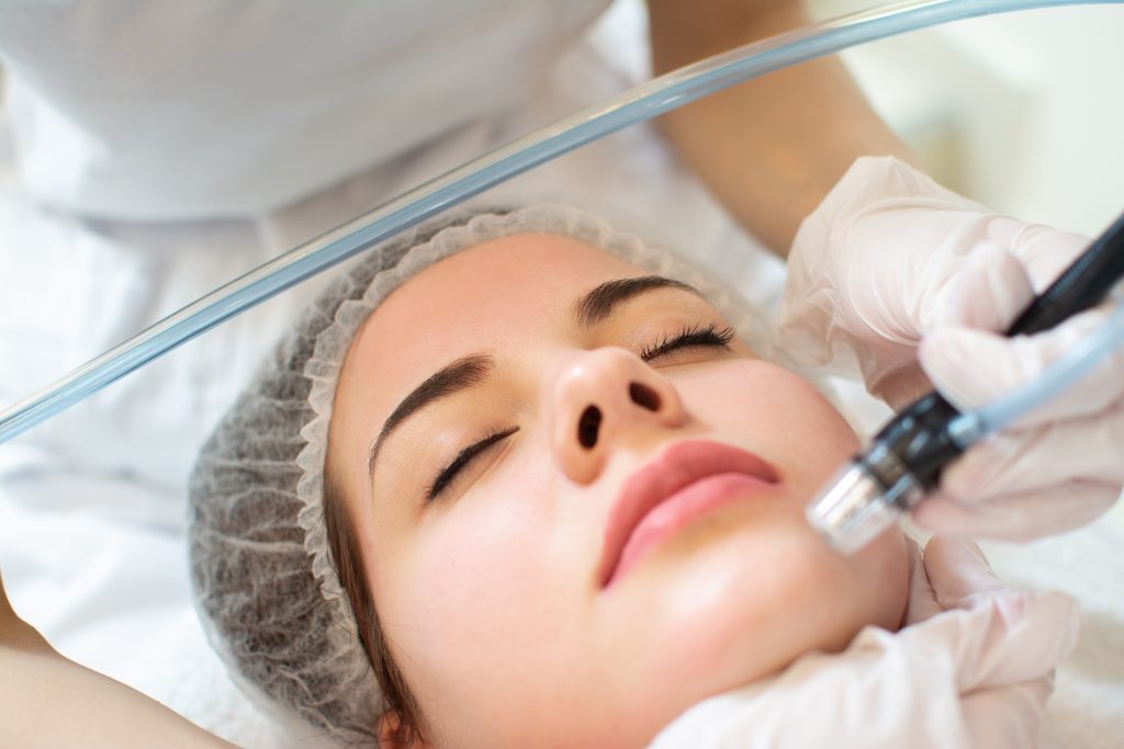 Closeup headshot of young woman receiving hydrafacial therapy at a clinic