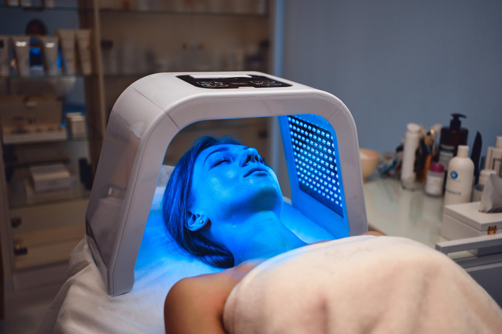 A young woman takes care of her skin with an LED mask