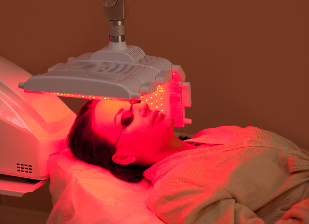 Woman lying on a table with protect glasses on eyes have a led therapy treatment